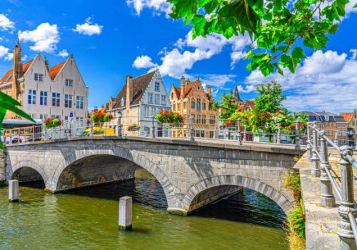 Bruges cityscape, Carmersbrug across Langerei water canal, arch bridge and medieval houses on promenade embankment in sunny day, Brugge old town, Bruges city historic centre, Flemish Region, Belgium